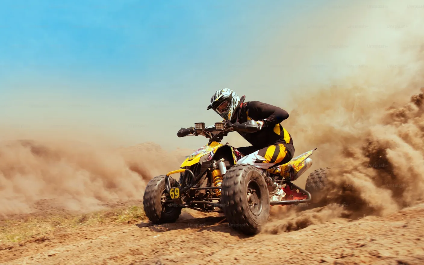 ATV rider racing through a dusty trail